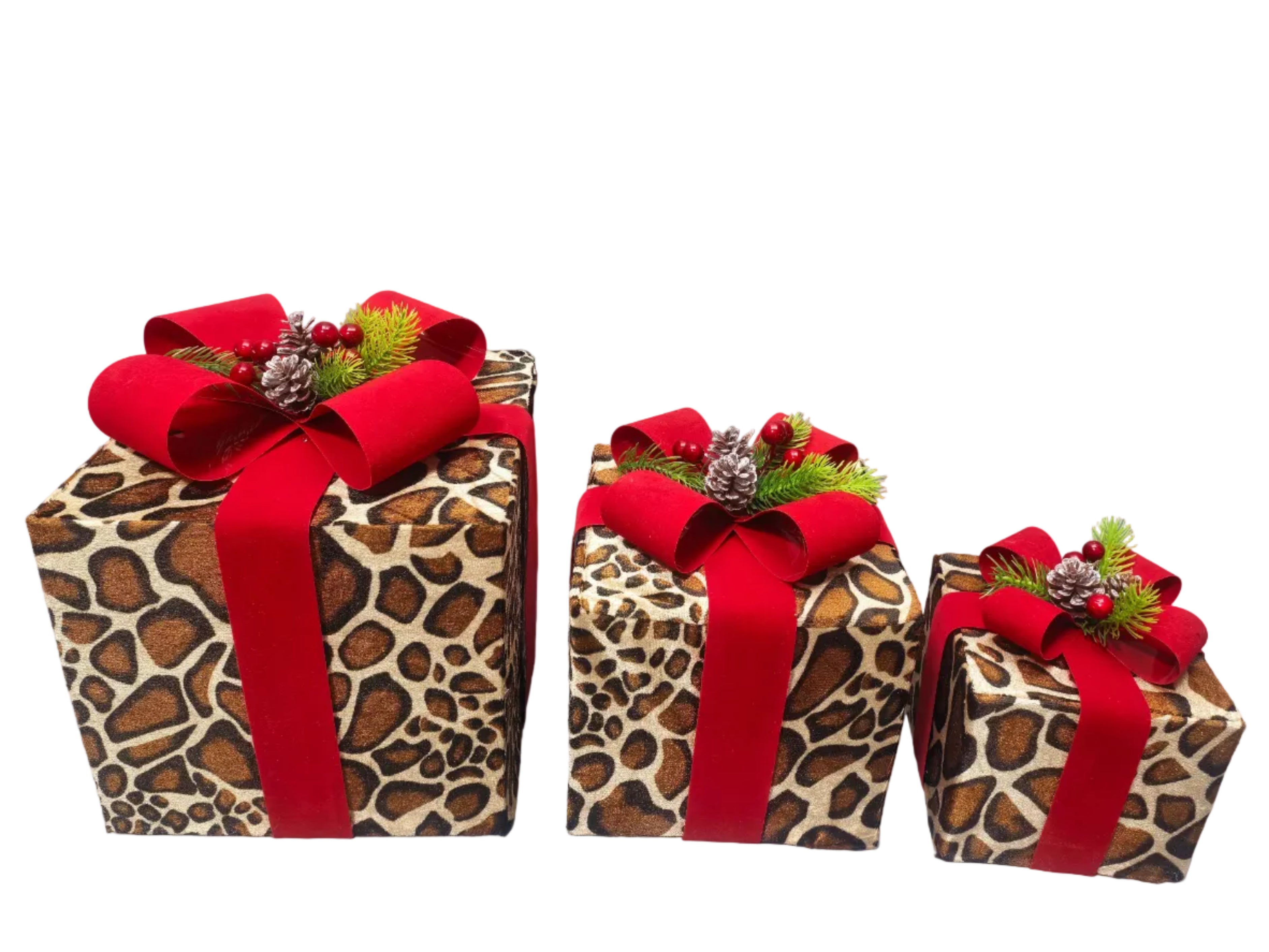 Three Christmas gift boxes wrapped in animal print material, each adorned with a large red ribbon bow, red berries, pinecones, and green artificial foliage, arranged from largest to smallest.