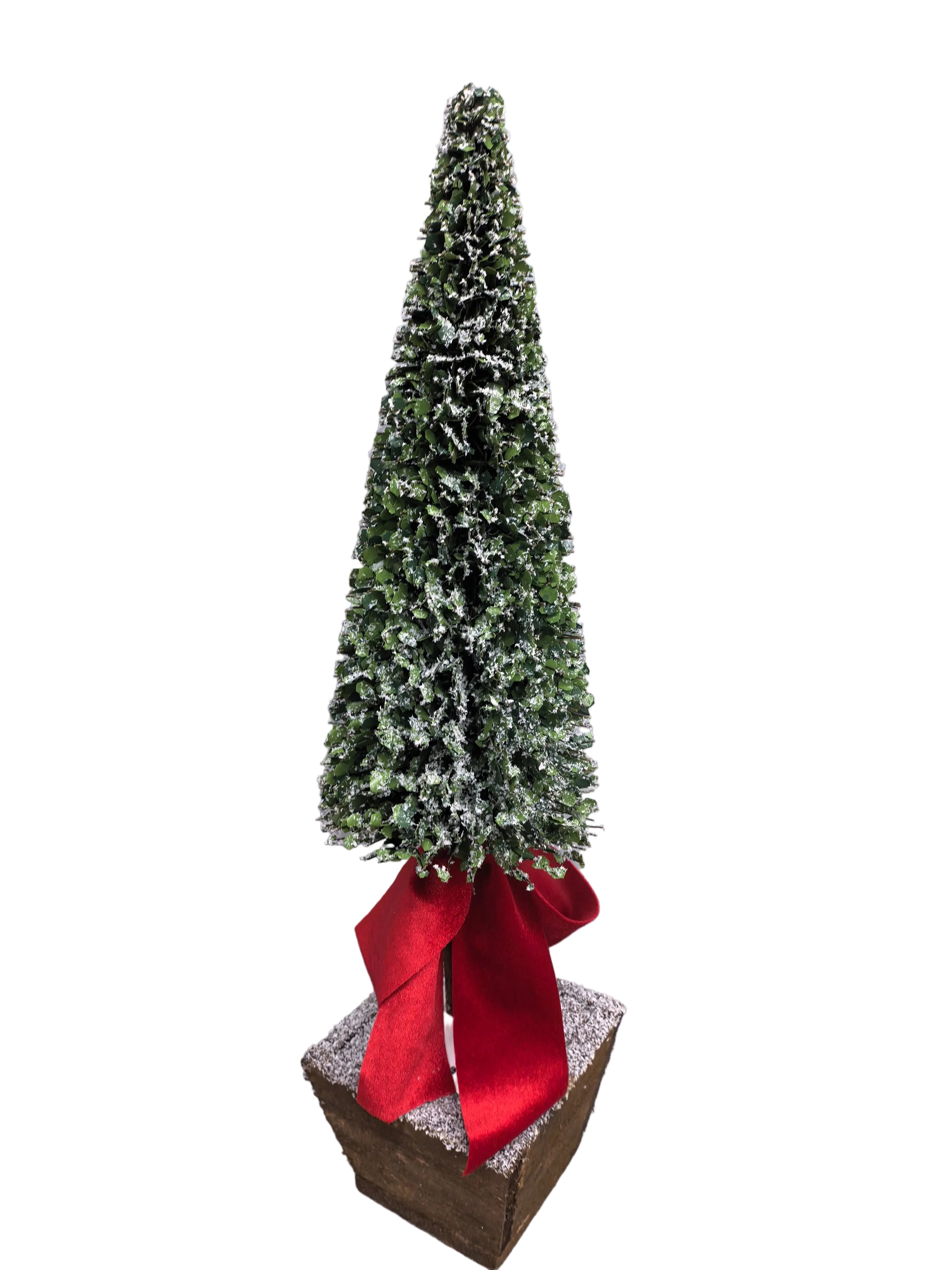 A small artificial Christmas tree with dense green foliage and white faux snow, tied with a large red ribbon at the base, set in a square brown box.