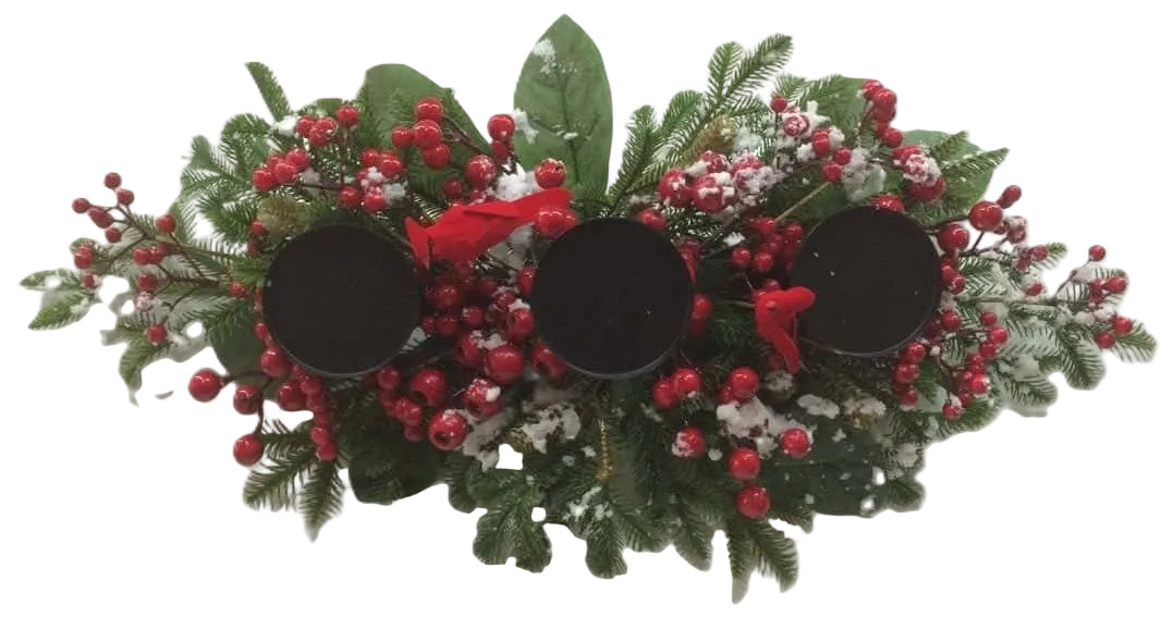 A festive Christmas wreath centerpiece with green pine branches, red berries, white snow-like accents, and three black oval candle holders.