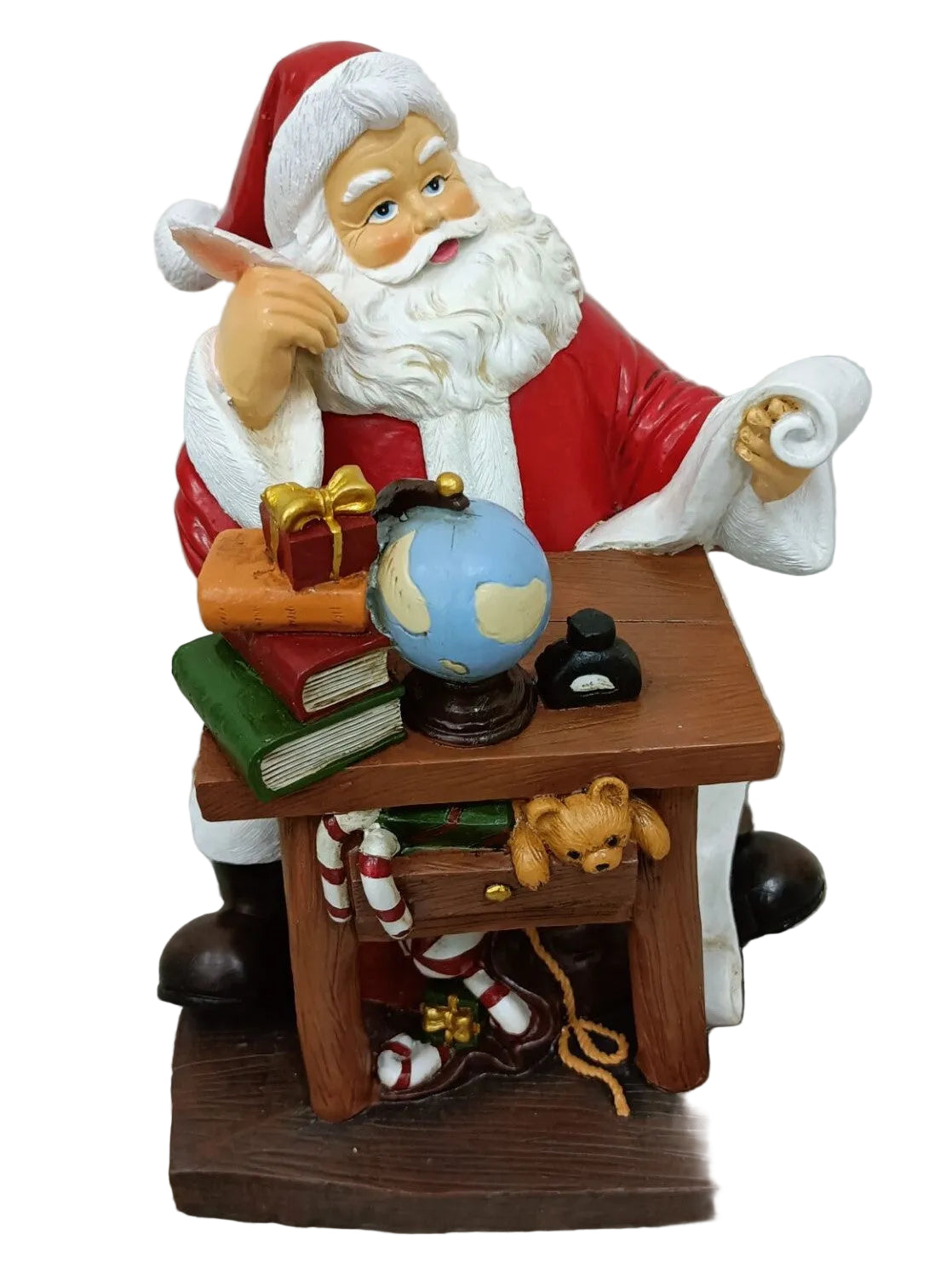 A resin figurine of Santa Claus sitting at a desk with a world globe, books, a teddy bear, and a Christmas stocking.