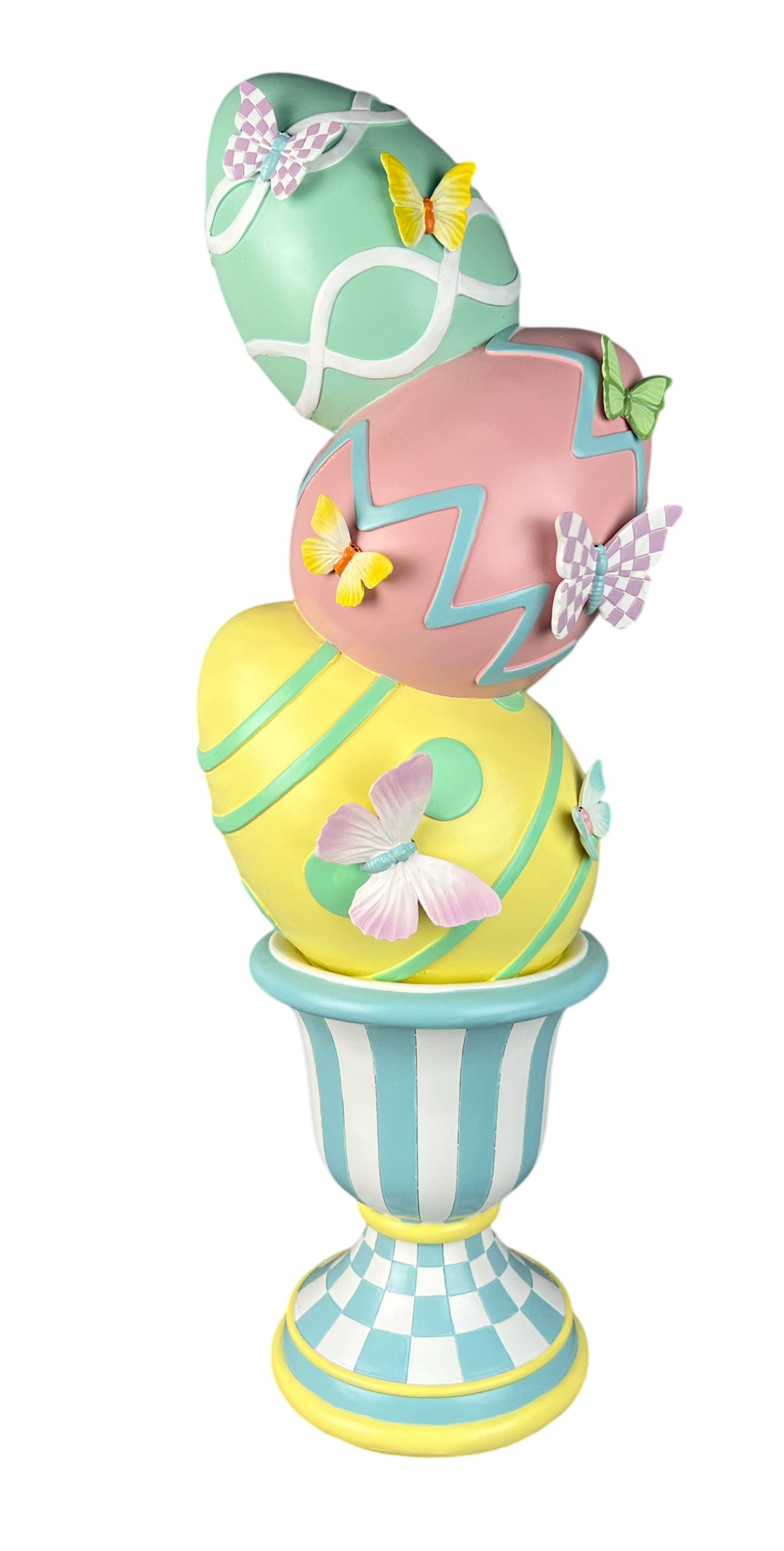 A decorative Easter egg sculpture stacked inside a striped pedestal cup, featuring pastel green, pink, and yellow eggs with butterfly and geometric patterns on a white background.
