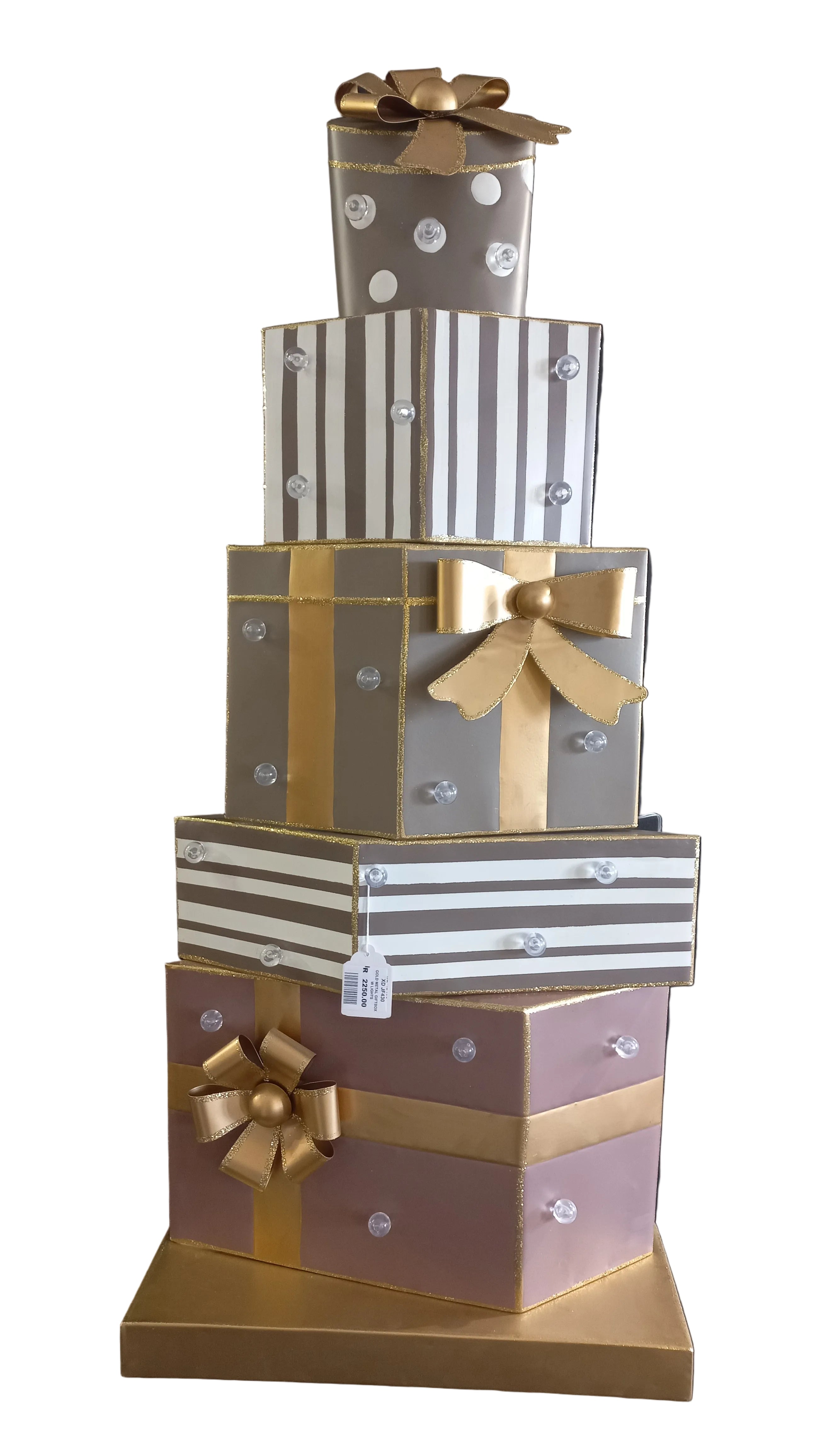 A gold, white, silver metal gift box stacked with lights, each adorned with gold and silver decorations and bow ribbons.