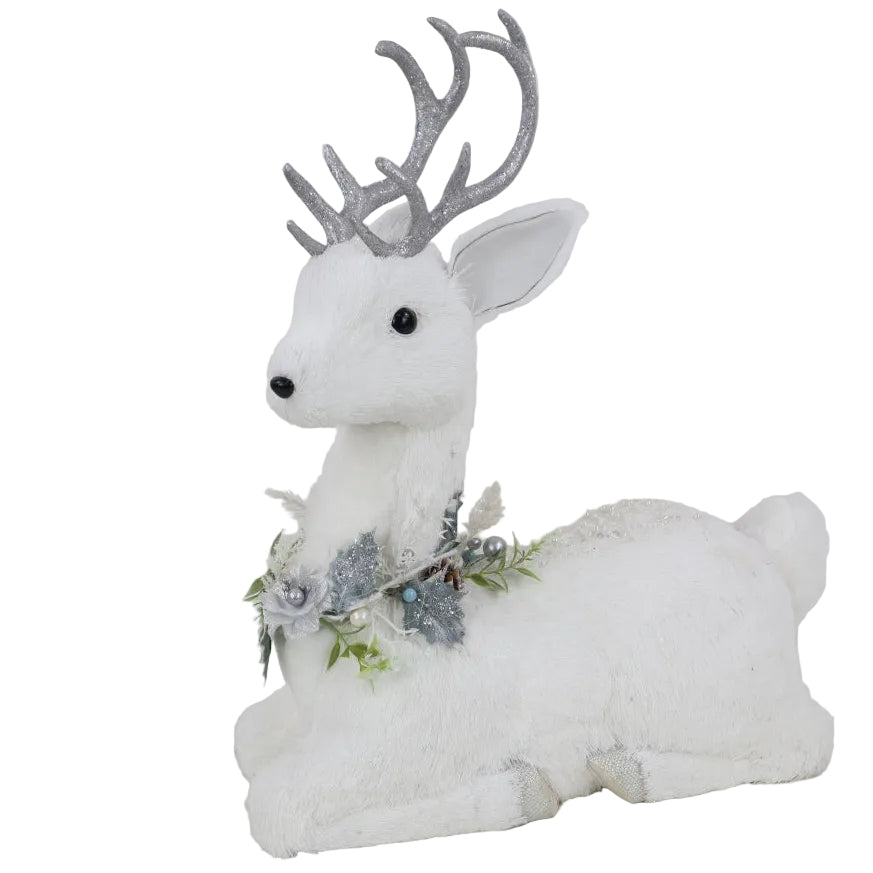 A white faux-fur reclining deer figurine with silver glittery antlers and a silver floral garland around its neck.