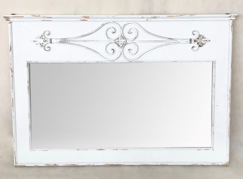 A distressed white wooden mirror with decorative elements on the frame